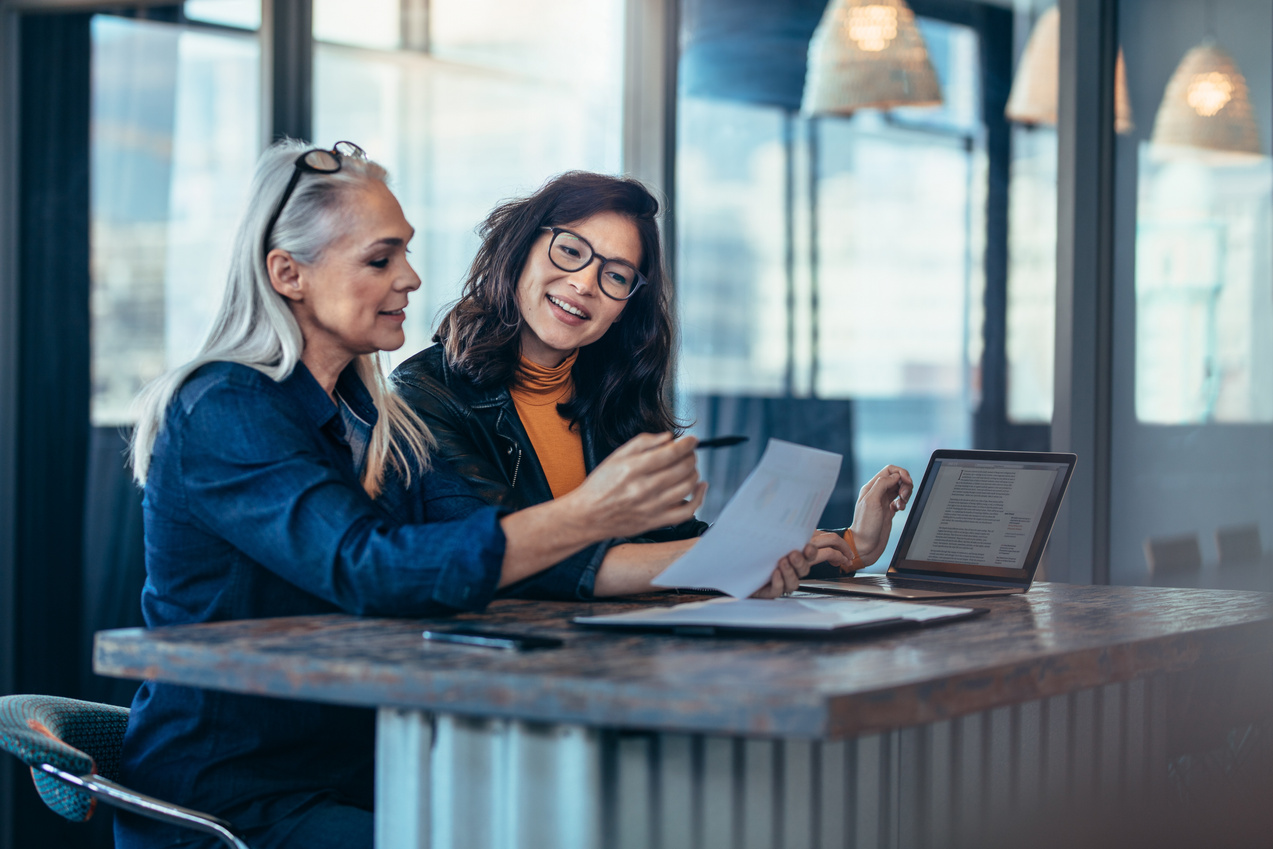 Two Women Analyzing Documents at Office